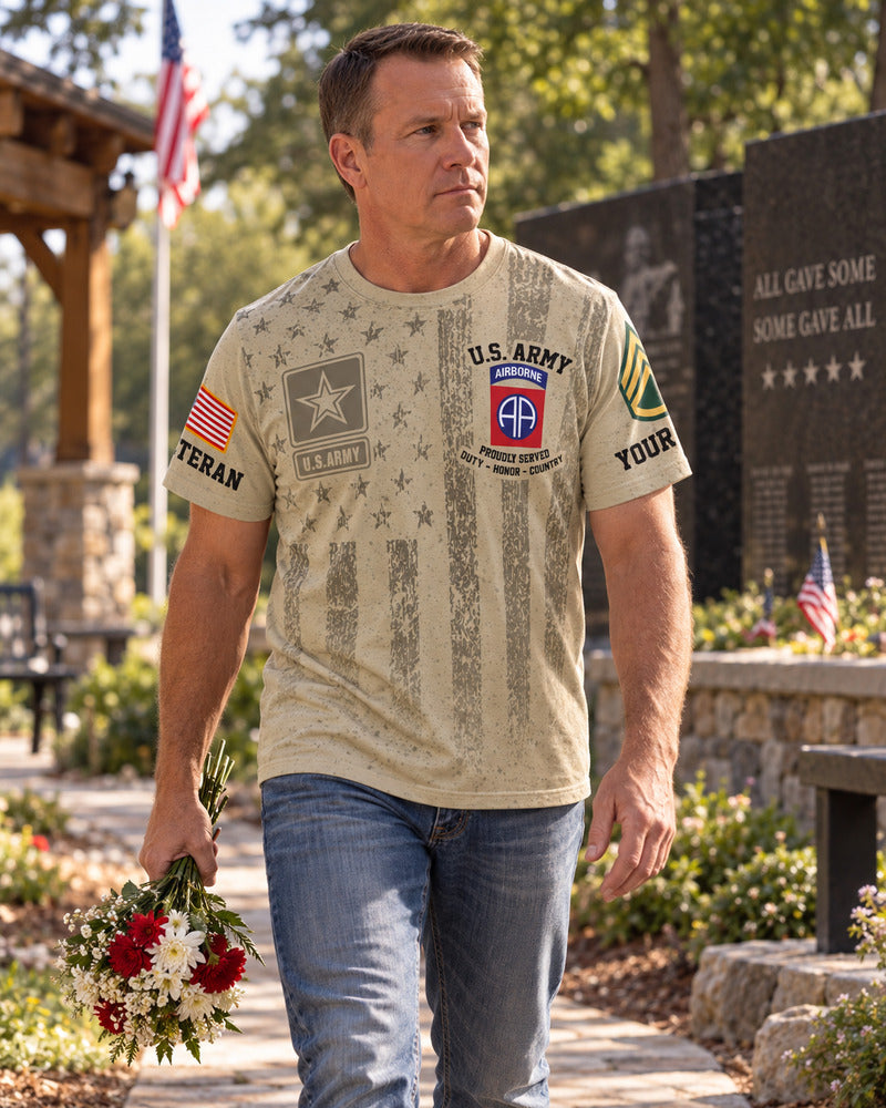 A man carrying flowers along a memorial garden path in an Army T-shirt.