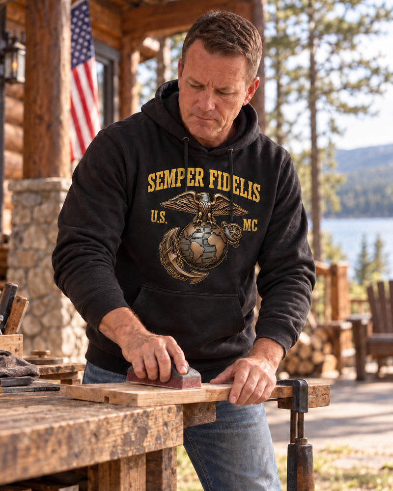 A man sanding a board in a Marine Corps hoodie.