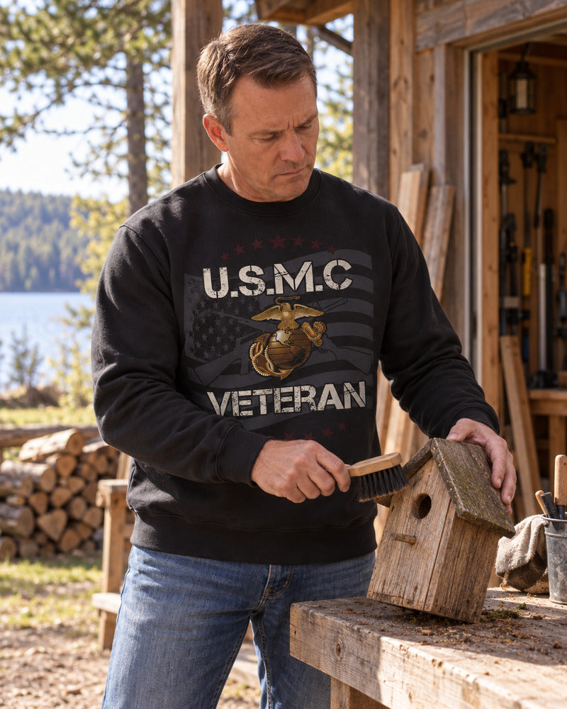 A man cleaning a birdhouse in a Marine Corps sweatshirt.