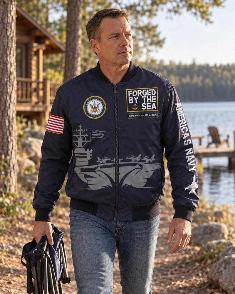 A man carrying a camp chair in a Navy bomber jacket.