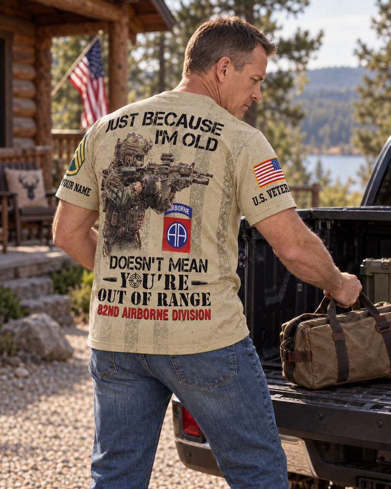 A man loading a bag into a pickup, showing the back and name sleeve of an Army AOP T-shirt.