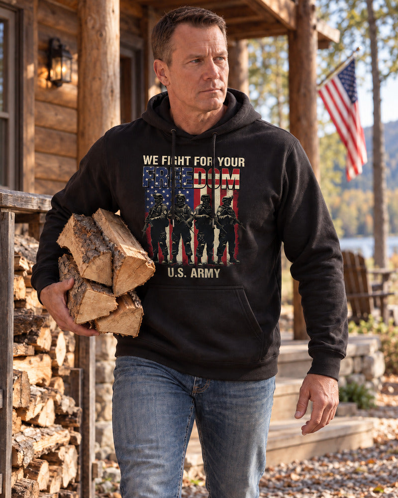 A man carrying firewood in an Army hoodie.